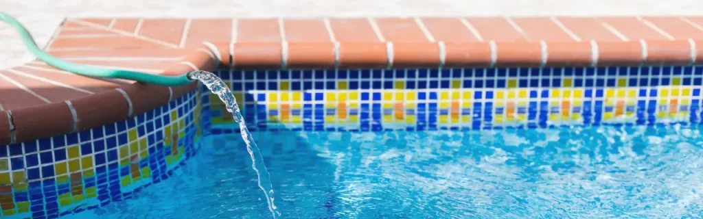 Hose filling up a pool Horizontal Article Images A garden hose filling up an outdoor pool.