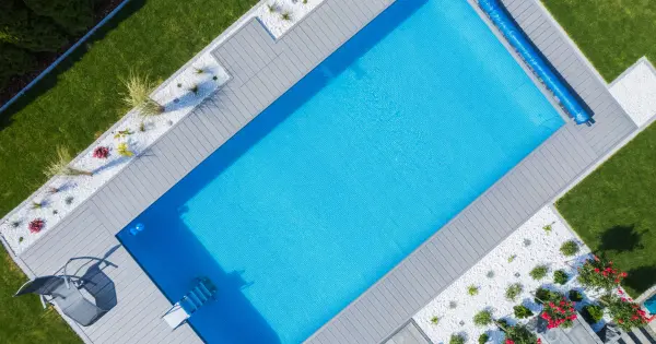 Drone view of a clear in-ground pool with cover removed, showing sparkling water and pool surroundings.