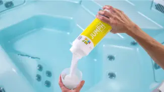 FROG® Jump® being poured into a TruDose™ cap above a hot tub to increase pH and maintain balanced water chemistry.