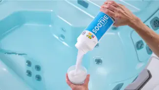 FROG® Soothe® being poured into a TruDose™ cap above a hot tub — raises total hardness for balanced, comfortable water.